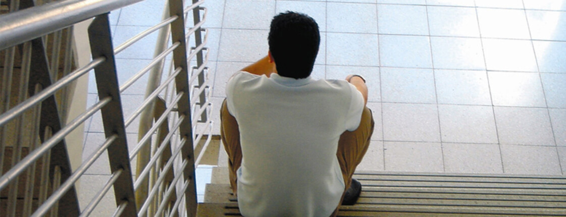 Ein Mann sitzt alleine auf einer Treppe.