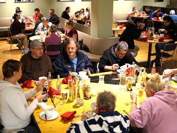 Menschen sitzen an einem Esstisch und unterhalten sich