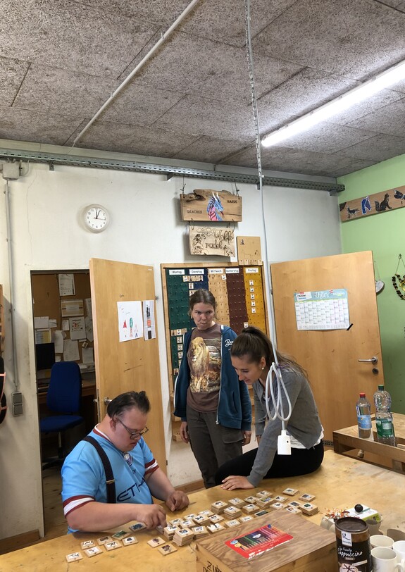 Klient mit Behinderung und Freiwilliger arbeiten in einer Werkstatt