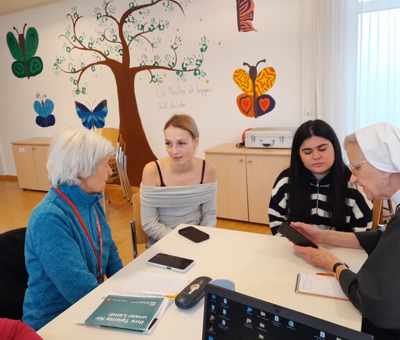 Zwei Mädchen erklären sei älteren Frauen das Smartphone