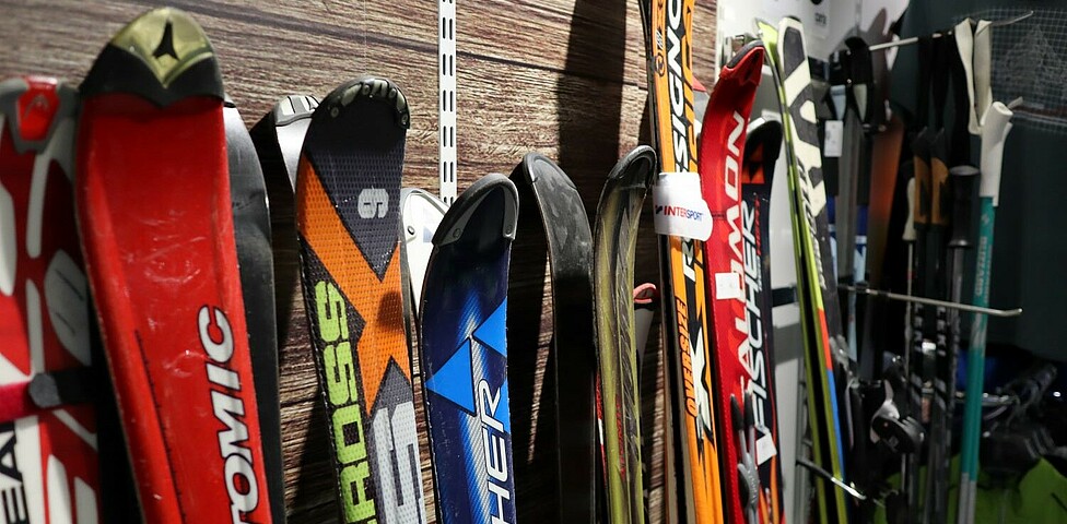 Skier und Skistöcke sind in einer Reihe nebeneinander aufgestellt