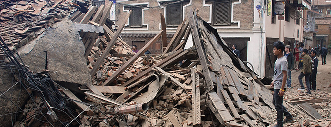 Ein Mann in Nepal steht vor einem zerstörten Haus