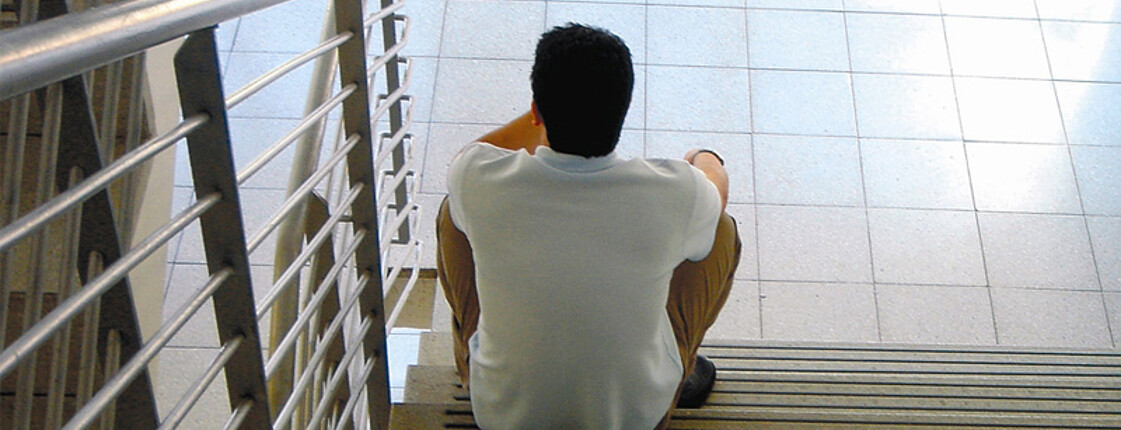 Ein Mann sitzt alleine auf einer Treppe.