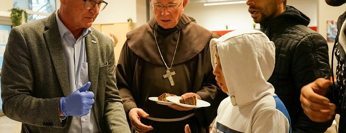 Caritas Direktor Johannes Dines und Erzbischof Franz Lackner verteilen Kuchen an obdachlose Menschen im Haus Elisabeth.