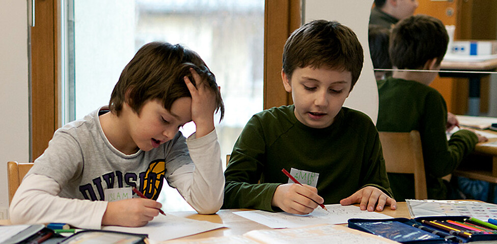 Zwei Schüler beim Hausaufgaben machen im Lerncafé der Caritas Salzburg