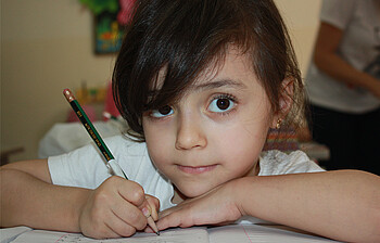 Ein kleines Mädchen schreibt in der Schule.